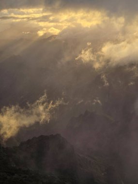 Sabah güneşi, Pico do Arieiro 'daki kalın bulutları delip geçiyor, Madeira' nın gizemli dağ sırtlarını ve vahşi iç dünyasını vurguluyor..