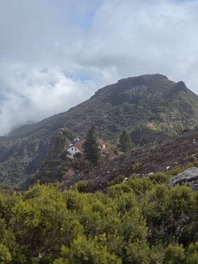 Bulutlar denizinin üzerinde, Pico Ruivo 'nun kayalık tepeleri gökyüzüne doğru uzanıyor, uçsuz bucaksız bir mesafede tek başına görünen bir bina..