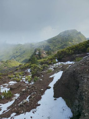  Pico Ruivo 'nun tepeleri, uzaktaki küçük bir ev engin dağlık araziyi demirlerken.