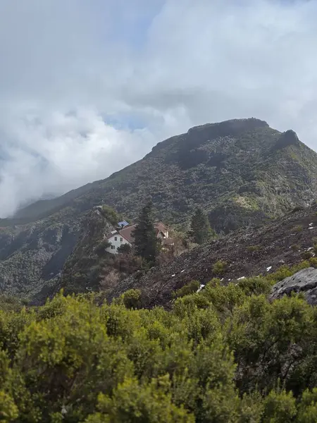 Bulutlar denizinin üzerinde, Pico Ruivo 'nun kayalık tepeleri gökyüzüne doğru uzanıyor, uçsuz bucaksız bir mesafede tek başına görünen bir bina..