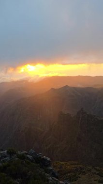 Altın sabah ışığında yıkanan Pico do Arieiro sürüklenen bulutların üzerinde yükselir. Barışçıl ışıltı ve yumuşak gökyüzü vahşi doğaya doğru sakin, güneşli bir kaçış yaratır..