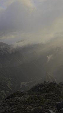 Pico do Arieiro, bulutların altında sürüklenirken sabah güneşinde yıkandı. Altın bir parıltı Madeira 'nın engebeli tepelerini ısıtıyor. Sisin üzerinde barışçıl bir başlangıç sunuyor..