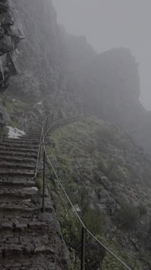 Sisli dağ merdivenleri Pico do Arieiro 'dan Madeira, Portekiz' deki Pico Ruivo yoluna çıkıyor. Volkanik kaya ve bulut ormanları boyunca dramatik ve korunmasız bir dağ yolu..