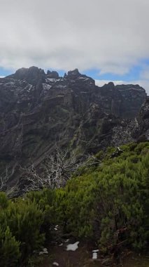 Madeiras adasının tepesinde, Pico Ruivo süprizleri kar tanecikli subtropikal yeşil ve alp beyazı ile gerçeküstü bir dağ sahnesinde.