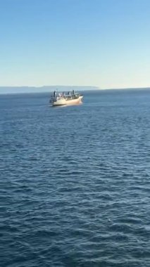Faroe Adaları yakınlarındaki sakin Kuzey Atlantik 'te ufuk çizgisinde uzak kıyı şeridi olan açık bir gökyüzünün altında yelken açan balıkçı teknesi..