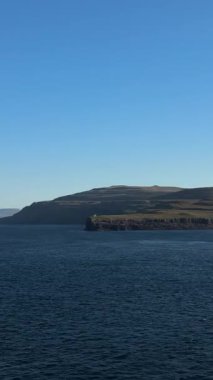 Faroe Adaları 'nın kayalık kıyı şeridi. Önünde derin Atlantik suları olan açık mavi bir gökyüzünün altında. Uzak ve vahşi Kuzey Atlantik manzarası.