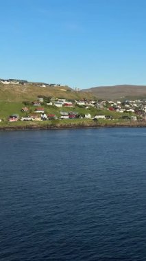 Trshavn manzarası, Faroe Adaları başkenti, renkli İskandinav evleri, huzurlu bir liman ve parlak bir yaz gökyüzü altında yemyeşil tepeler. İdeal seyahat hedefi.