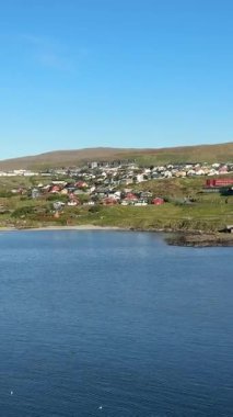 Renkli evleri, yeşil tepeleri ve berrak mavi gökyüzünün altındaki Kuzey Atlantik sularıyla Faroe Adaları 'nın başkenti Trshavn' ın manzarası.. 