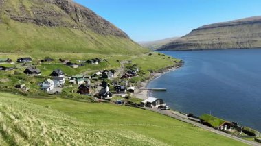 Faroe Adaları, Vgar Adası 'ndaki bir köy. Çarpıcı fiyort manzarası, yeşil yamaçlar ve dramatik sahil kayalıkları arasında yuva yapmış ikonik kuzeyli evler..