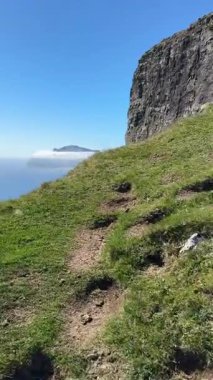 Faroe Adaları, Vgar Adası 'ndaki Trlanpan boyunca dar uçurum kenarında. Atlantik üzerinde dik bazalt duvarlar yükseliyor