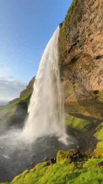 Güney İzlanda 'da Seljalandsfoss şelalesi, gün batımında arkadan izleniyor.. 