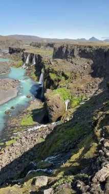 İzlanda Dağlık Bölgesi 'ndeki Sigldugljfur Kanyonu' nda, kristal berraklığında şelaleler yosunlu lav duvarlarından volkanik arazide dalgalanan canlı mavi bir nehre dökülüyor..