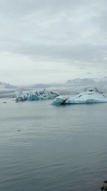 İzlanda 'daki JkulsrIn Buzul Gölü, Vatnajkull Buzulu tarafından beslenen, bulutlu gökyüzünün altında yüzen buzdağlarına ev sahipliği yapar..