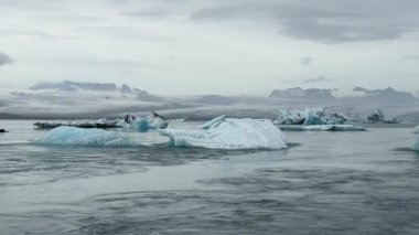 Yüzen buzdağları Jkulsrln Gölünde parıldıyor, İzlanda 'nın muhteşem Arktik harikalar diyarının arkasında yükselen Vatnajkull Buzulu ile.