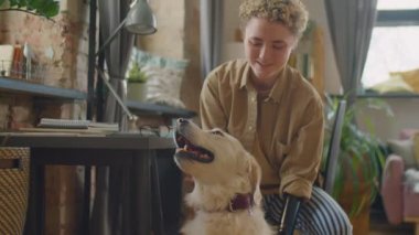 Protez kollu neşeli beyaz kızın evde sevimli Golden Retriever köpeğini okşamasını.