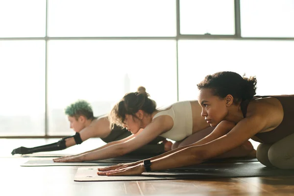 Group of young girls exercising in team on the floor in yoga class