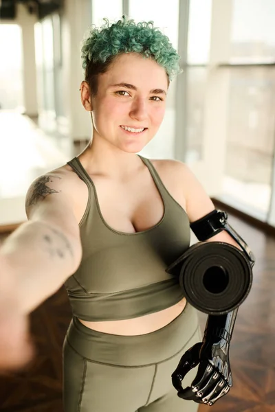 Portrait of young woman with disability making selfie portrait while training in gym