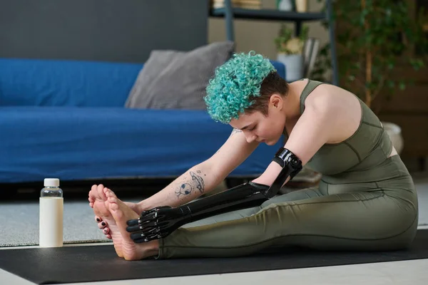 Woman with prosthetic arm exercising on exercise mat during training at home