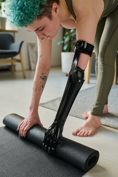 Girl with prosthetic arm using exercise mat for sport training at home