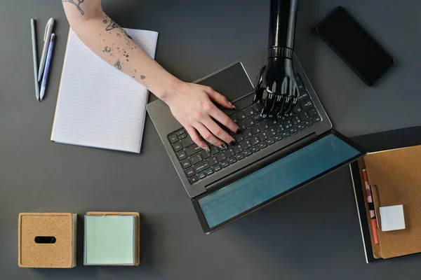 High angle view of woman with prosthetic arm typing on laptop working online