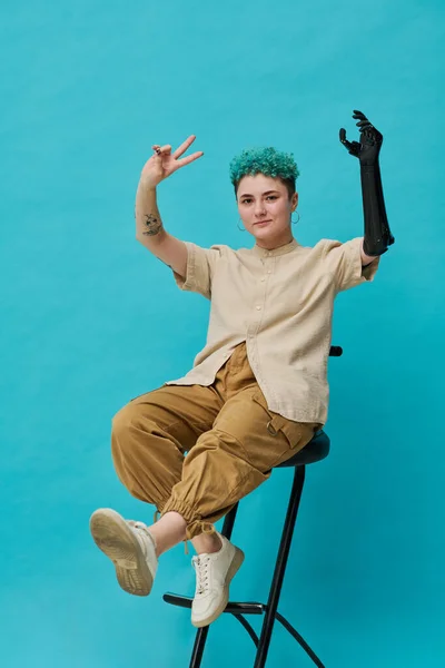 Κάθετη Εικόνα Της Έφηβης Προσθετικό Χέρι Κάθεται Στην Καρέκλα Μπλε — Φωτογραφία Αρχείου