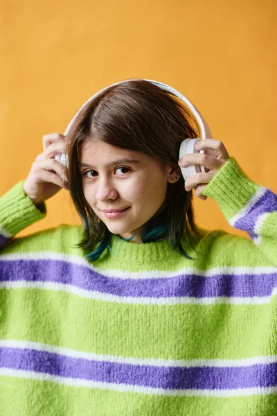 用无线耳机听橙色背景音乐的少女画像 — 图库照片