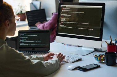 Bilgisayarda güvenlik kodunu yazan genç programcının iş yerinde monitörün önünde oturması.