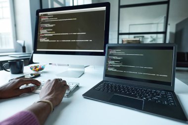 Bilgisayarda bilgisayar kodları yazan programcının IT ofisinde çalıştığı sırada yakın plan görüntüsü.