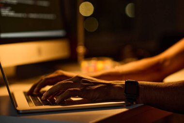 Masada oturan ve karanlık ofiste çalışan genç programcıların yakın plan fotoğrafları.