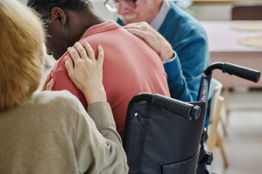 Depresyondaki adamı destekleyen, tekerlekli sandalyede oturan insanlar terapiyi ziyaret ediyorlar.
