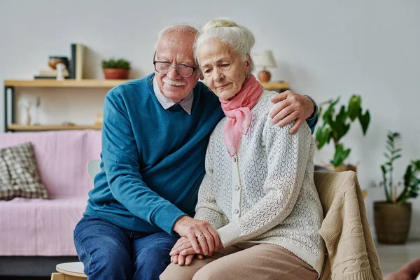 老年人忧心忡忡地拥抱着他的妻子 当他们坐在房间里的椅子上的时候 他们支持着她 — 图库照片