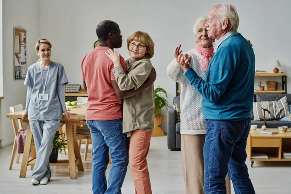 Group of senior people learning to dance during lesson with caregiver watching for them