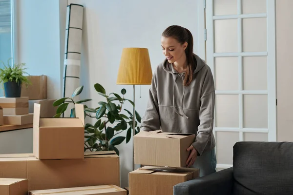 Young woman putting packed cardboard boxes with things in stack during the move