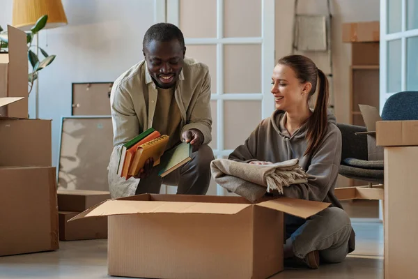 Multiethnic Young Couple Putting Books Cardboard Boxes Move New House — Stock Photo, Image