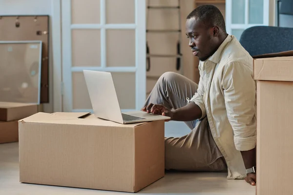 Αφροαμερικάνος Που Κάθεται Στο Πάτωμα Ανάμεσα Συσκευασμένα Κουτιά Και Ψάχνει — Φωτογραφία Αρχείου