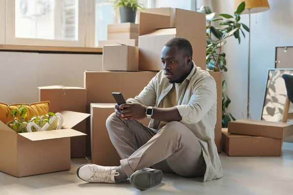 Hombre Afroamericano Sentado Suelo Con Cajas Cartón Fondo Uso Teléfono —  Fotos de Stock