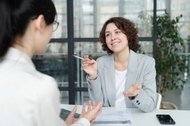 Masadaki iş görüşmesi sırasında adayla çalışma anlarını tartışan genç mülakatçı