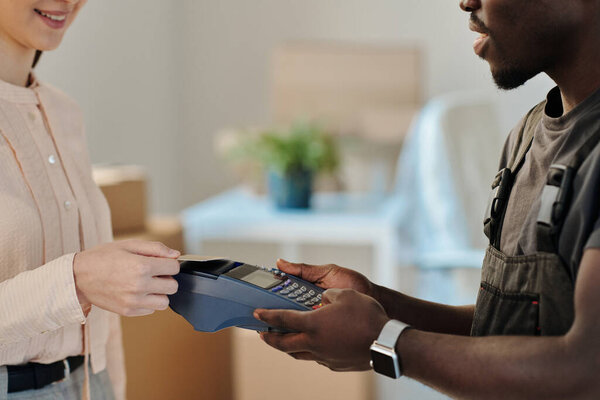 Close-up of young woman paying for service with credit card for moving