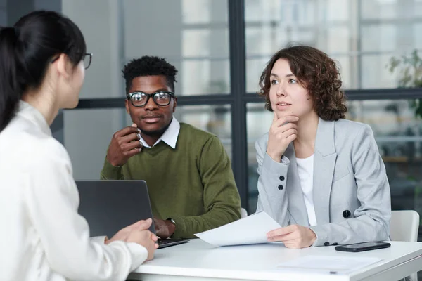 Business people asking questions to candidate while sitting at table during job interview