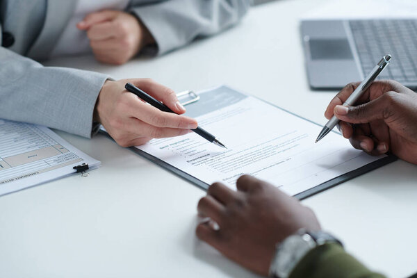 Close-up of candidate filling the form for new job at table during job interview
