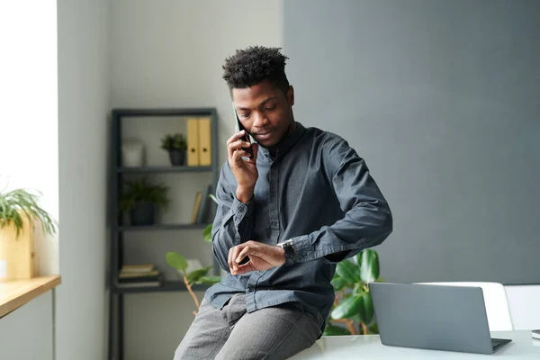 アフリカ系アメリカ人のビジネスマンが携帯電話で会話をしているのを見ながら 同僚と会うのを待っている — ストック写真