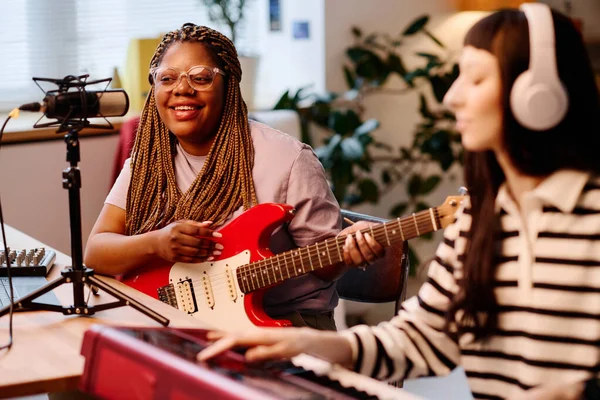 非洲裔美国妇女一边弹吉他 一边和她的朋友一起录音 — 图库照片