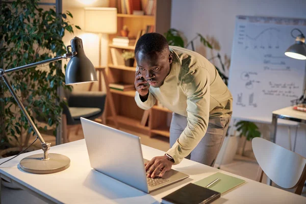 Jovem Empresário Africano Usando Laptop Mesa Enquanto Conversa Celular Com — Fotografia de Stock