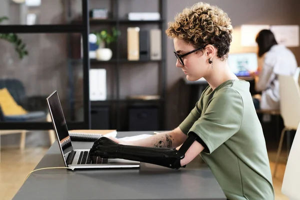 Ofis Masasında Otururken Dizüstü Bilgisayarda Yazan Protez Kollu Genç Bir — Stok fotoğraf