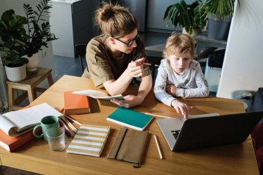 Küçük çocuk dizüstü bilgisayar kullanıyor ve özel hocalarıyla internet üzerinden çalışıyor.