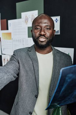 Ofiste röntgen görüntüleriyle çalışan Afrikalı erkek radyoloğun portresi