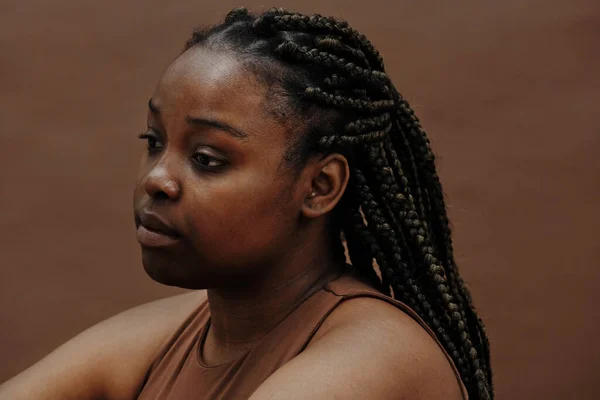 Zwarte Jonge Vrouw Met Vlechten Zitten Met Blanco Uitdrukking Tegen — Stockfoto