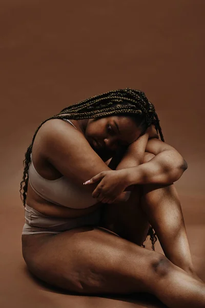 Portret Van Afrikaanse Mollige Vrouw Ondergoed Zit Tegen Bruine Achtergrond — Stockfoto