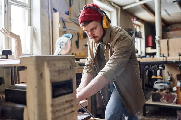 Joven Carpintero Masculino Que Usa Auriculares Que Cancelan Ruido Utilizando — Foto de Stock