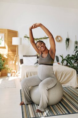 Afrikalı genç bir kadın hamileliği boyunca yatak odasında spor yapıyor.